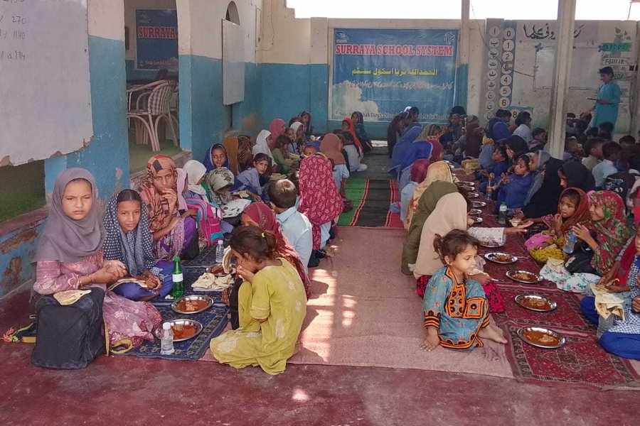 Children at Surraya Free School sharing a cooked meal together on the floor.